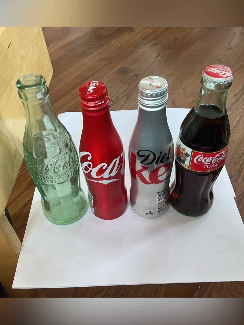 Set of Four Coke Bottles, three unopened and one Classic Bottle